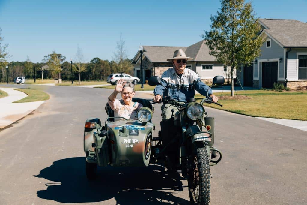 Couple riding in motorcycle with sidecar in front of the Cottages